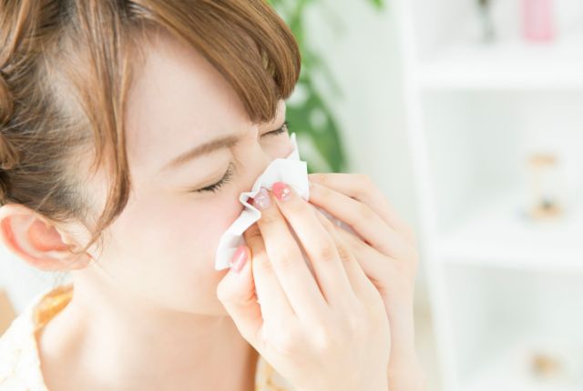 鼻をかみながら辛そうにしている女性